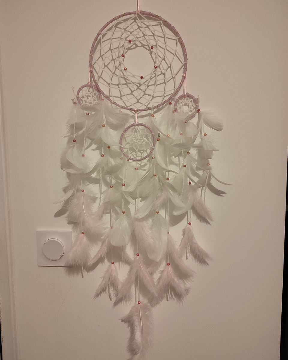 Attrape-rêves artisanal aux plumes roses confectionné pour une cérémonie d'enfant