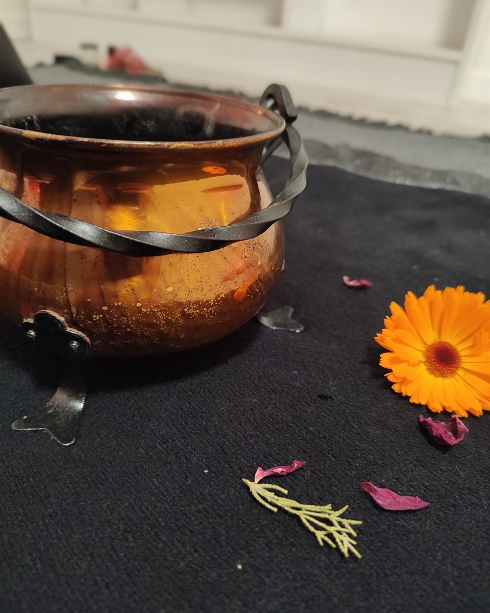 Chaudron de cuivre et fleurs pour un rituel païen de libération et de mémoire